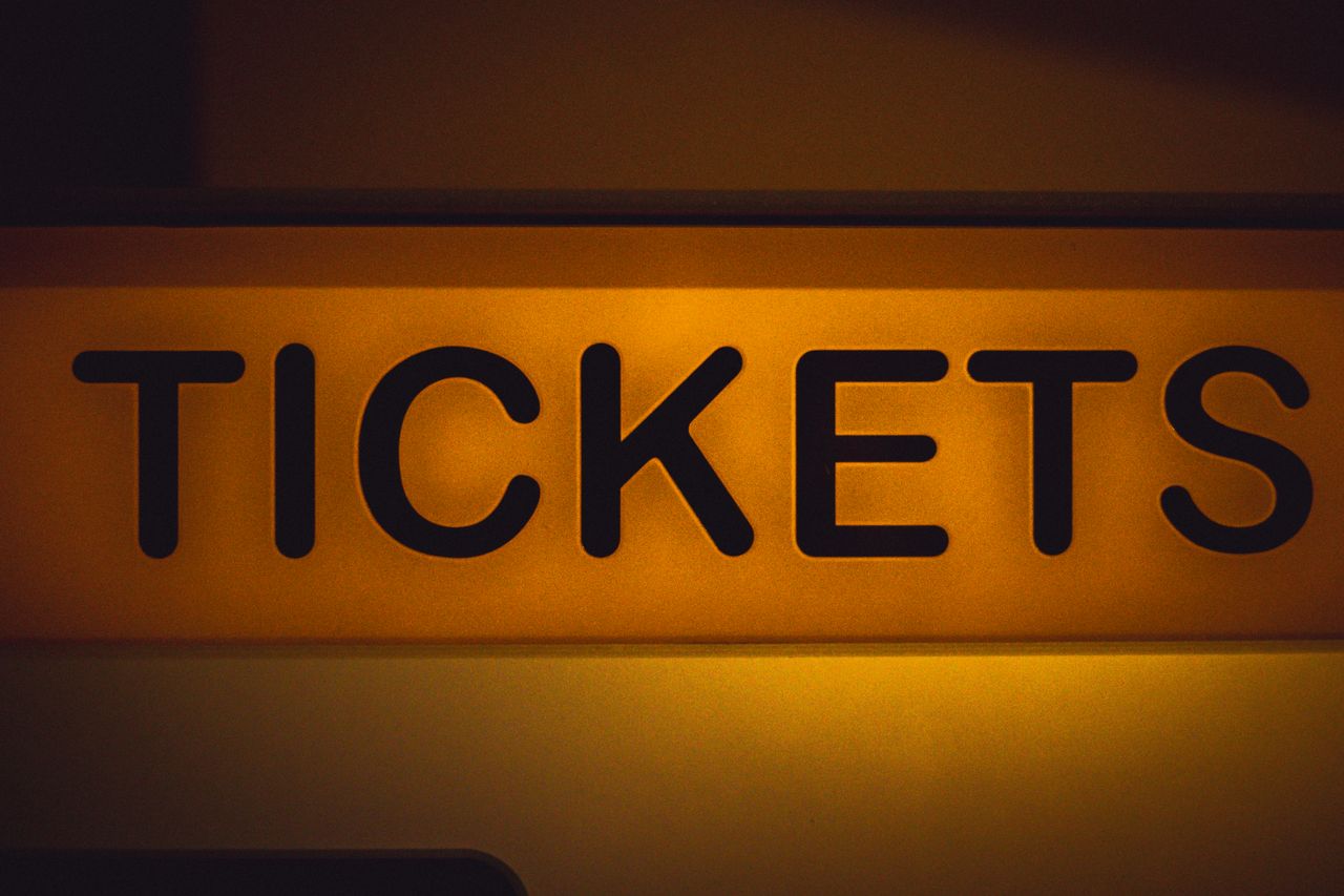 services-02 Close-up of an illuminated yellow ticket sign against a dark background.
