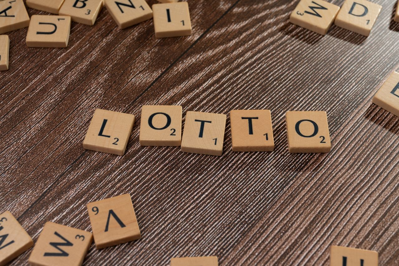 services-04 Scrabble tiles spelling 'LOTTO' on a wooden table surface, symbolizing chance and gaming.