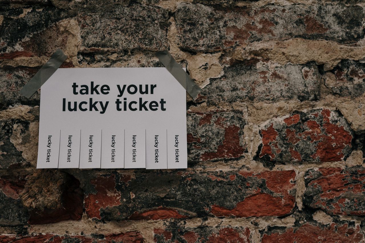services-03 Close-up of a 'Take Your Lucky Ticket' sign taped to a rustic brick wall.