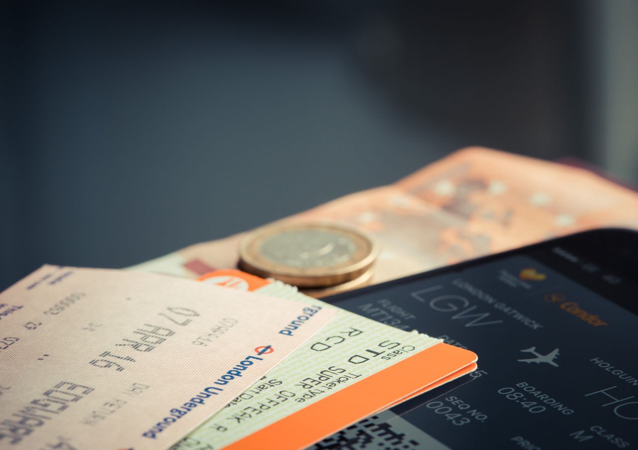 hero-services Airline ticket with euro coins and smartphone displaying flight details.