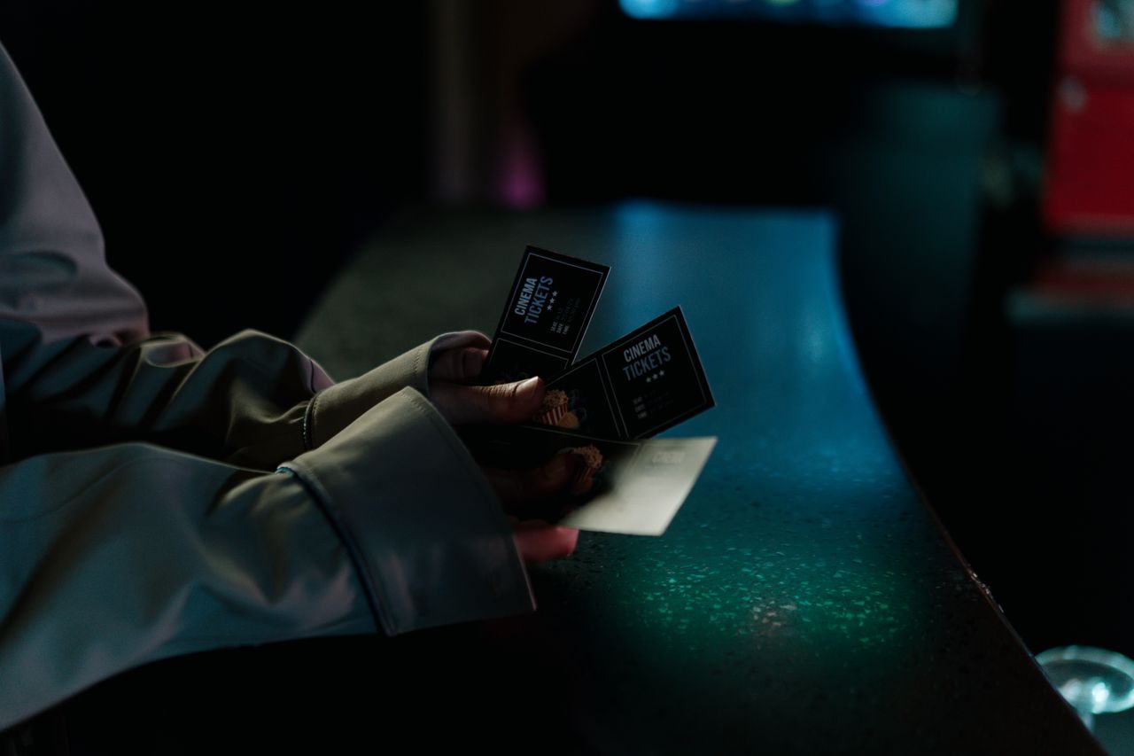 hero-about Moody image of a person holding cinema tickets at night, highlighting anticipation of a movie night.