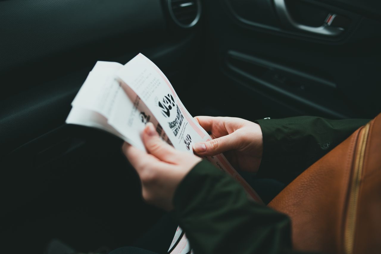 impact-img Close-up of hands holding a brochure inside a car, creating an intimate and focused scene.